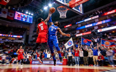 NBA季后赛激战图 - 两名球员在篮下争抢，观众席上球迷激动呐喊